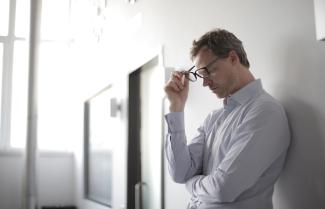 Man with glasses leaning against a wall